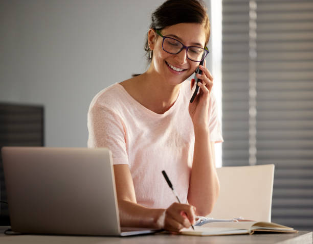 istock Shot of a young woman making a phone call using her smartphone while working from home 1343547152