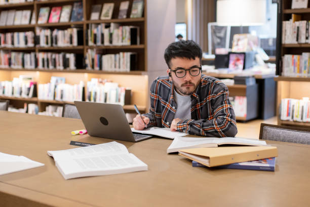 istock Young adult studying in a library 1343547238