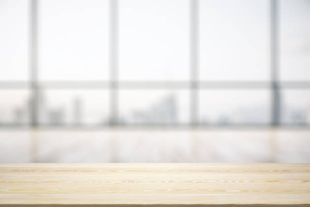 istock Blank wooden desk with light empty office room with big window on background, mock up 1343547334