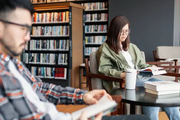 Two young adults reading in a library. Okayama, Japan