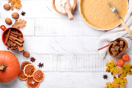 Pumpkin and food ingredients, spices, cinnamon and kitchen utencil on white rustic wooden background. Concept homemade baking for holiday. Cooking pumpkin pie and cookies for Thanksgiving day.