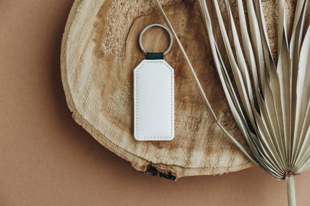 istock Keychain mockup among brown palm leaves to display design. Blank white sublimation key chain photo. 1343547452