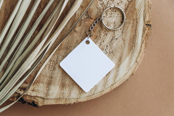 istock Keychain mockup among brown palm leaves to display design. Blank white sublimation key chain photo. 1343547457