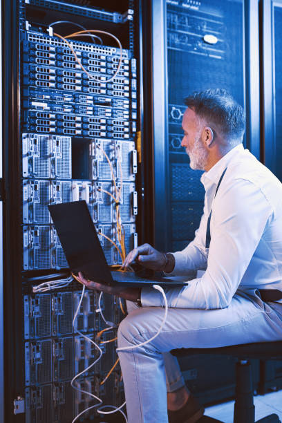 istock Shot of a mature man using a laptop while working in a server room 1343549304