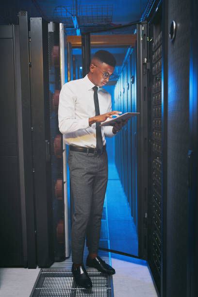 istock Full length shot of a young IT specialist standing alone in the server room and using a digital tablet 1343550743