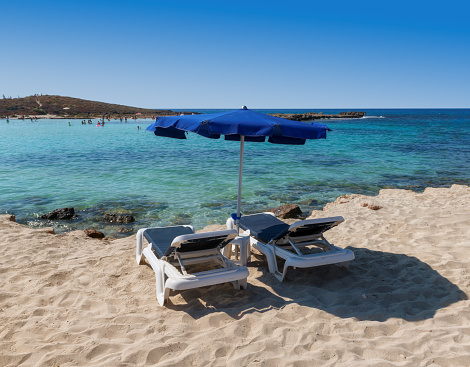 Beautiful Mediterranean beach. Beach umbrellas and sunbeds on sandy beach in Ayia Napa, Cyprus