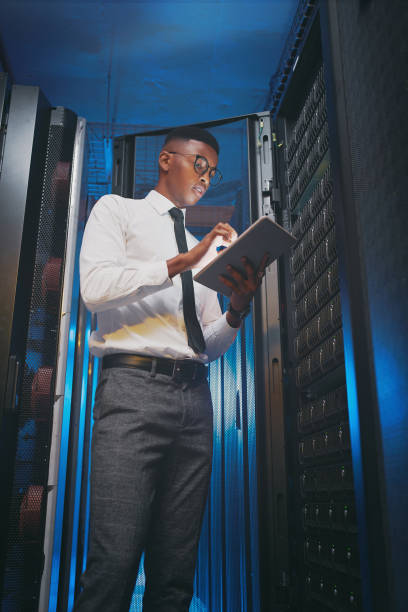 istock Shot of a young IT specialist standing alone in the server room and using a digital tablet 1343550760