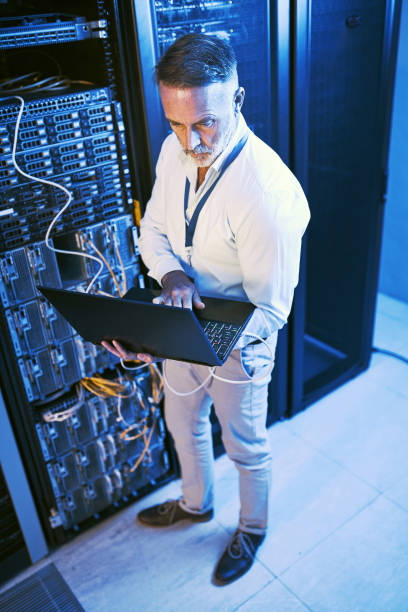 istock High angle shot  of a mature man using a laptop while working in a server room 1343550835