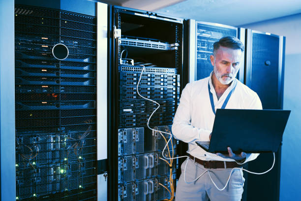 istock Shot of a mature man using a laptop while working in a server room 1343550836