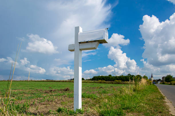 Rustic mailboxes in a row alongside a tree-lined, rural dirt road in the autumn season.  Country living.  Scenics.  Empty, remote area with no people. Sunlight coming through the background trees.  Texas, USA.  