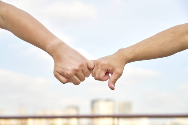 istock Two man fingers hooked together in front of blurred sky background 1343552984