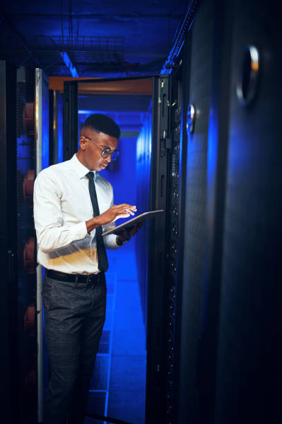 istock Shot of a young man using a digital tablet while working in a server room 1343553180