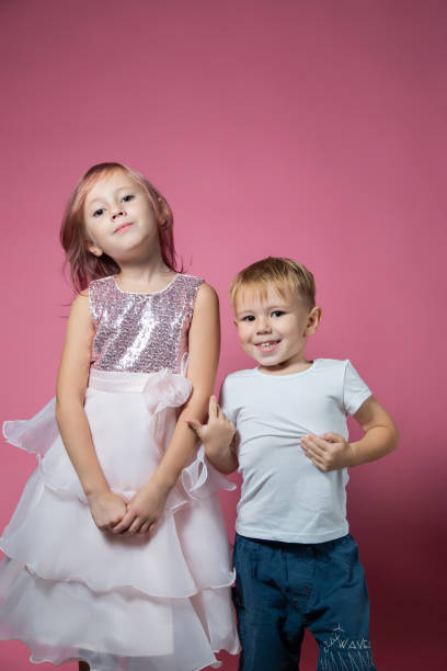 istock Caucasian brother and sister ,hugging on camera on pink background studio shot. 1343555479