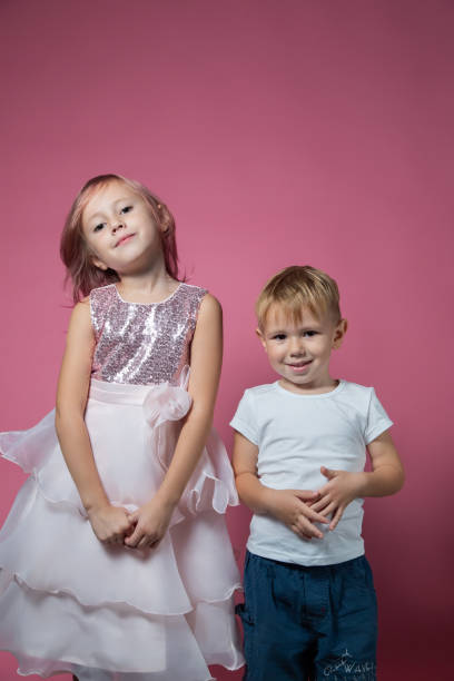 istock Caucasian brother and sister ,hugging on camera on pink background studio shot. 1343555483