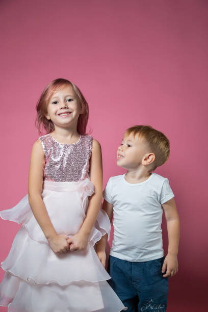 istock Caucasian brother and sister ,hugging on camera on pink background studio shot. 1343555495