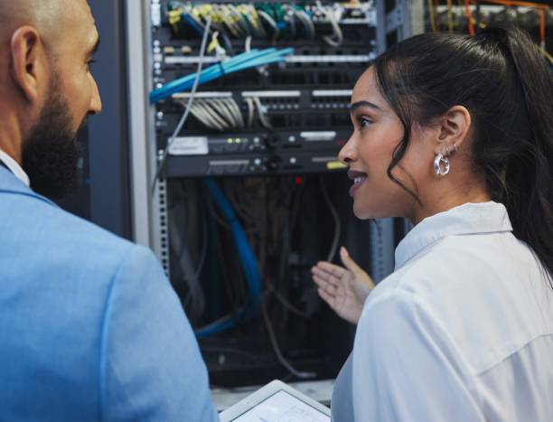 istock Shot of two workers inspecting the electronic equipment in a server room together at work 1343555584