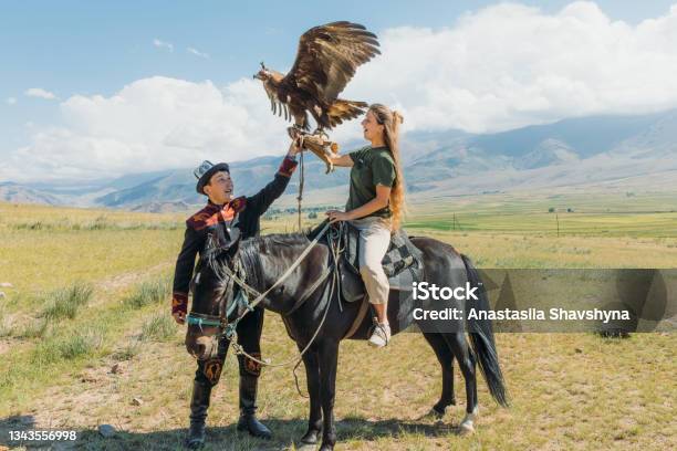 Woman Traveler Exploring The Old Traditions With Eagle Hunter In The Mountains Of Central Asia Stock Photo - Download Image Now