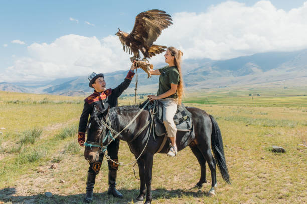 woman traveler exploring the old traditions with eagle hunter in the mountains of central asia - gobi desert imagens e fotografias de stock