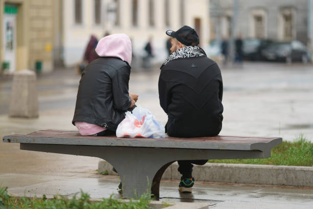 casal sentado no banco e conversando na rua da cidade de moscou - bench men puddle sitting - fotografias e filmes do acervo
