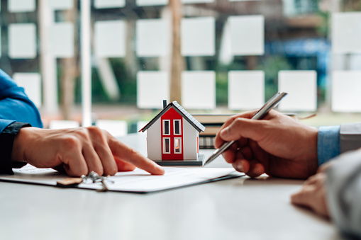 Los clientes interesados en comprar una casa firman una firma para celebrar un contrato de compra de vivienda con un agente de bienes raíces. Aprobación de préstamo hipotecario concepto de préstamo hipotecario y seguro. photo