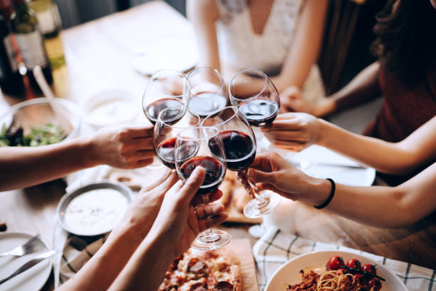 Close up shot of a group of joyful friends enjoying together, having fun and toasting with red wine during dinner party Close up shot of a group of joyful friends enjoying together, having fun and toasting with red wine during dinner party blind date stock pictures, royalty-free photos & images