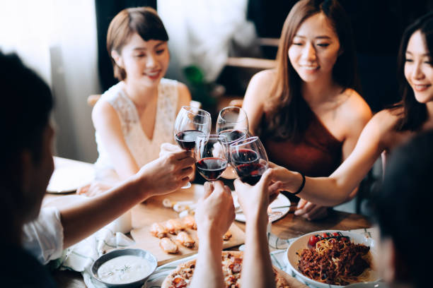 a young group of joyful friends enjoying together, having fun and toasting with red wine during dinner party - choicesea 個照片及圖片檔