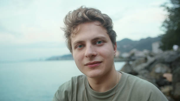istock Young blond boy towards camera making heart symbol with hand and smiling looking at camera 1343562604