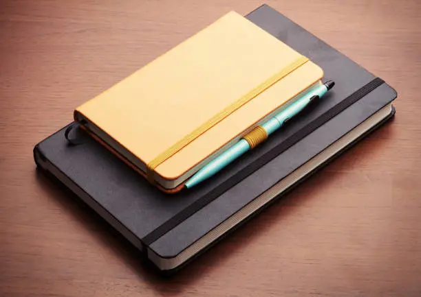 Close-up of two leather-bound copybooks on a wooden desk