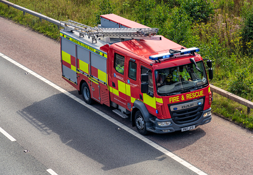 Lancashire, UK - Emergency lights illuminated on a fire engine as it is driven along the hard shoulder of a motorway towards the scene of an emergency.