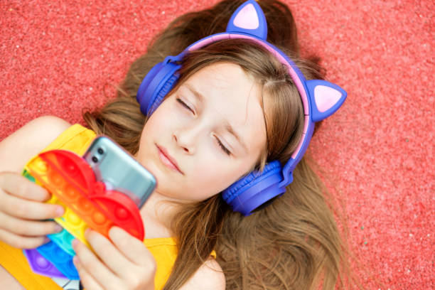 istock School girl with Pop It and smartphone 1343564780