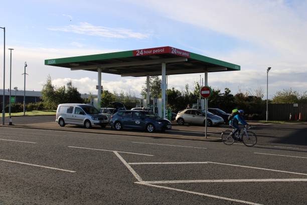 Cyclist and Cars at a Petrol Station Loanhead, Scotland - 28 September 2021 Cyclist going past cars stopped at an Asda supermarket petrol station near Edinburgh midlothian scotland stock pictures, royalty-free photos & images