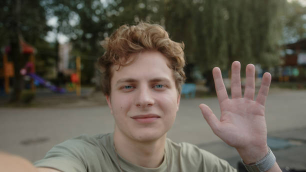 istock Young handsome boy with blond colored eyes is video calling or vlogging with the phone in his hand in a park outdoors 1343565808