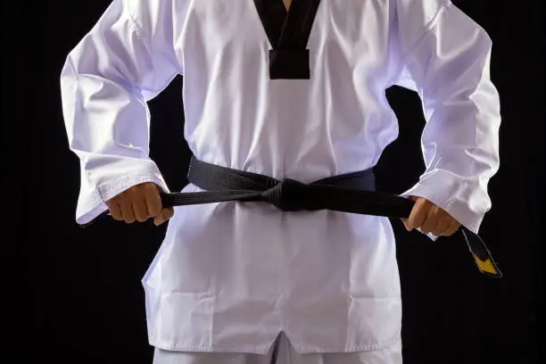 Photo of Close up Taekwondo martial arts fighter in white uniform two hands holding black belt