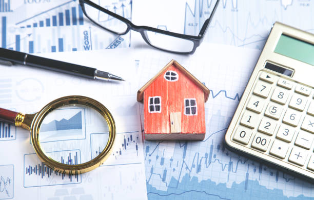 istock House model, magnifying glass, eyeglasses, pen, calculator on the financial graphs. 1343576557
