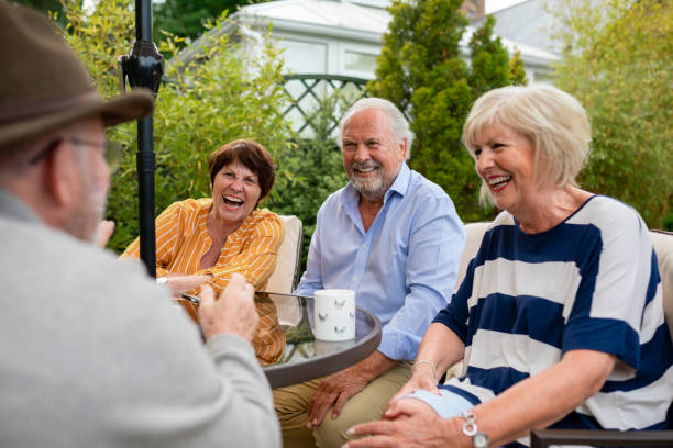 Friends Having a Laugh in the Garden Senior friends sitting in the garden on a summers day together. They are sitting and having a laugh over a cup of tea. seniors stock pictures, royalty-free photos & images