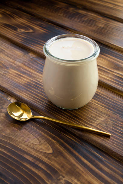 yogur casero en el frasco de vidrio sobre el fondo de madera marrón. producto lácteo fermentado. - cuajar fotografías e imágenes de stock