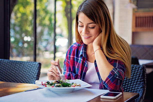 istock Young woman is eating salad in a restaurant 1343582998