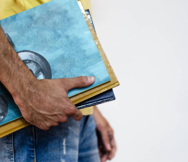side view of a young man holding several text books for study or work.