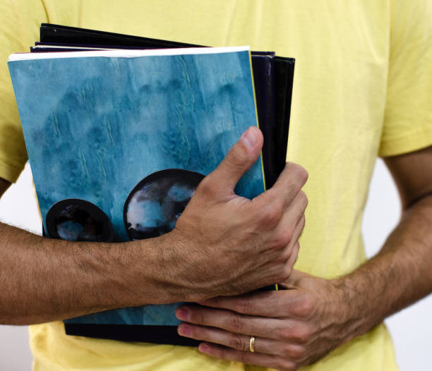 istock young man holding several text books for study or work. teacher with many books in his hands. 1343585713