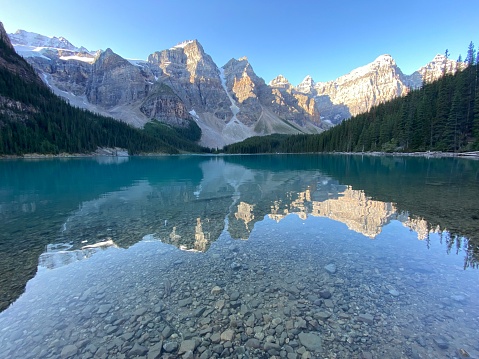 Reflections of mountains on moraine lake at dawn in Canada’s Rocky Mountains on a summer morning