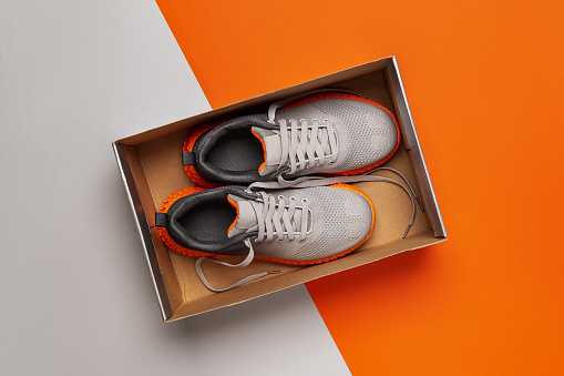 Nuevas zapatillas textiles en la caja sobre fondo gris naranja. photo