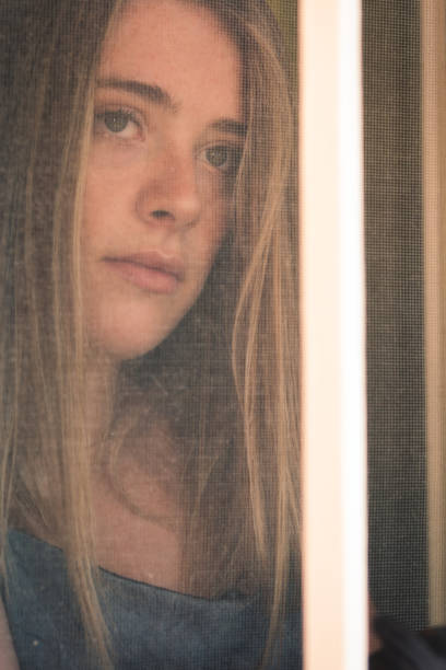 istock A pretty young blonde girl looking behind a window 1343590303