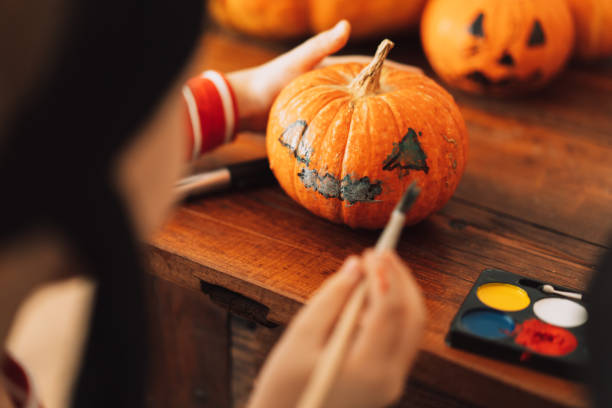 istock Boy dressed as pirate paints face on pumpkin 1343595181