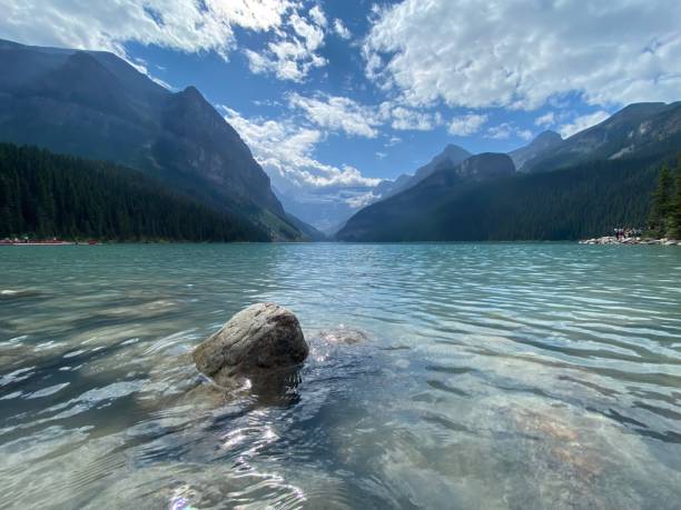 Image of lake Louise Alberta on a summer day with a rock in the foreground poking out of the water. This beautiful lake is the Canadian Rocky Mountains, Banff national park