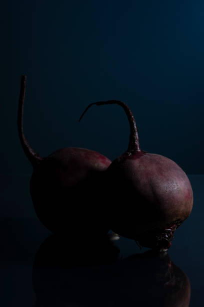 a pair of red beets on a black background minimalistic still life