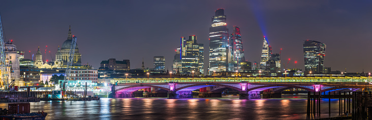 The iconic dome of St. Paul’s Cathedral, the glittering spires of the City skyscrapers and the futuristic towers of the South Bank overlooking the River Thames illuminated at night in the heart of London, the UK’s vibrant capital city.