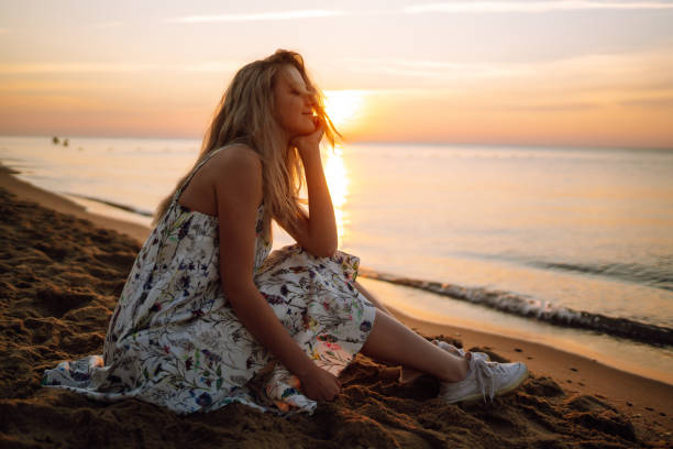 istock Young woman walks along seashore at sunset. 1343597562