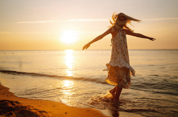 istock Young woman walks along seashore at sunset. 1343598599