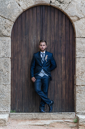Young caucasian groom with beard looking at the camera. Big door in the background