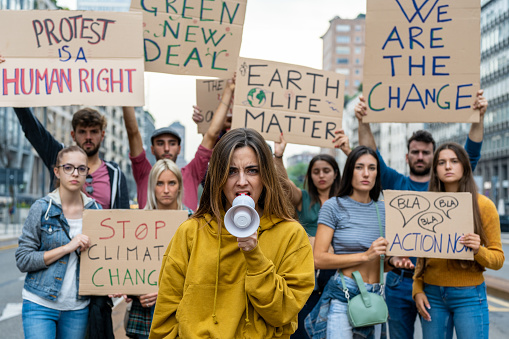 Group of multiethnic people making protest about climate change, public demonstration on the street against global warming and pollution.